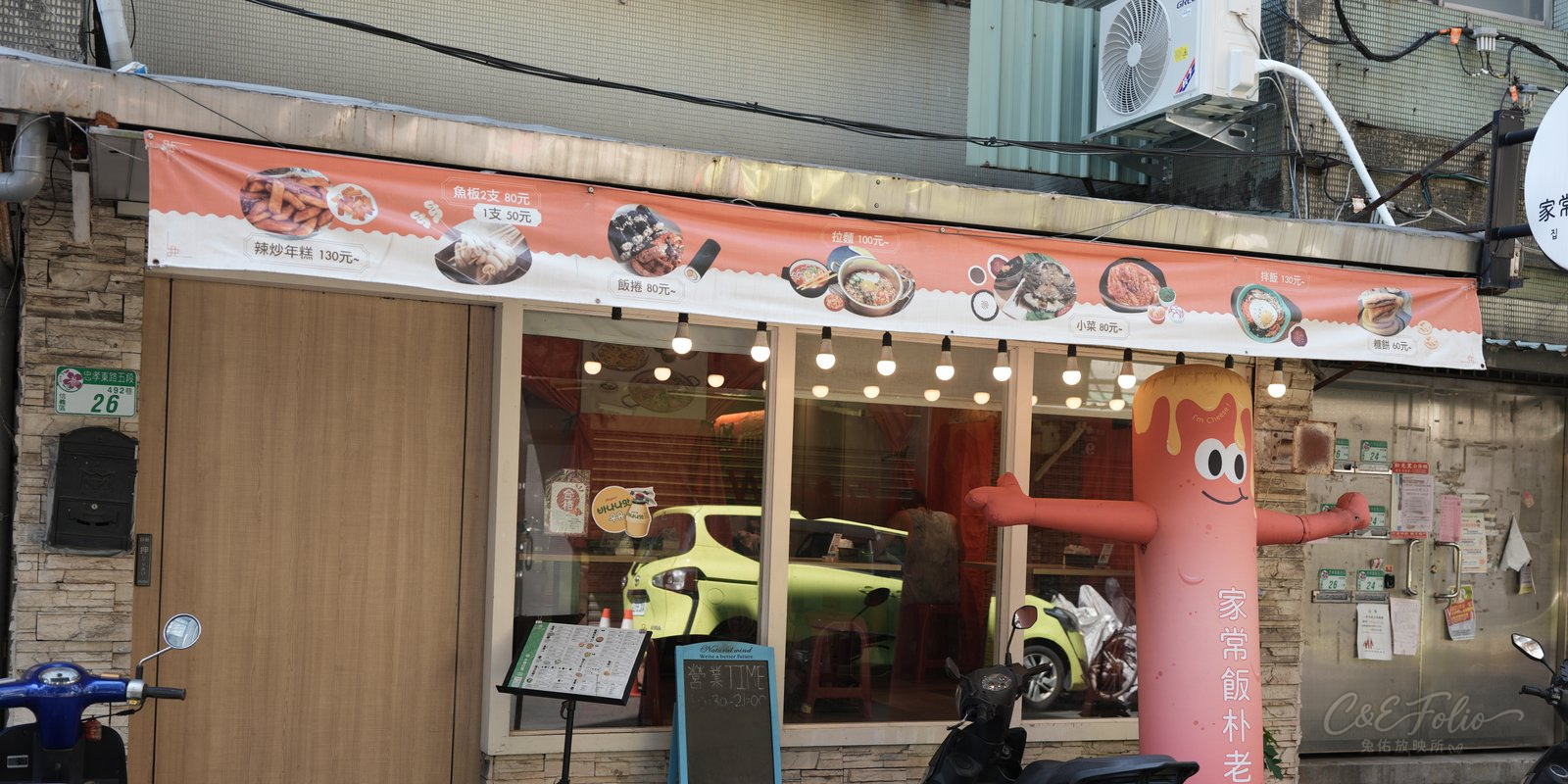 家常飯朴老師永春店門口,橘色價目布條與充氣人偶